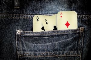 Das Bild zeigt 3 Spielkarten mit ASS in einer Hosentasche